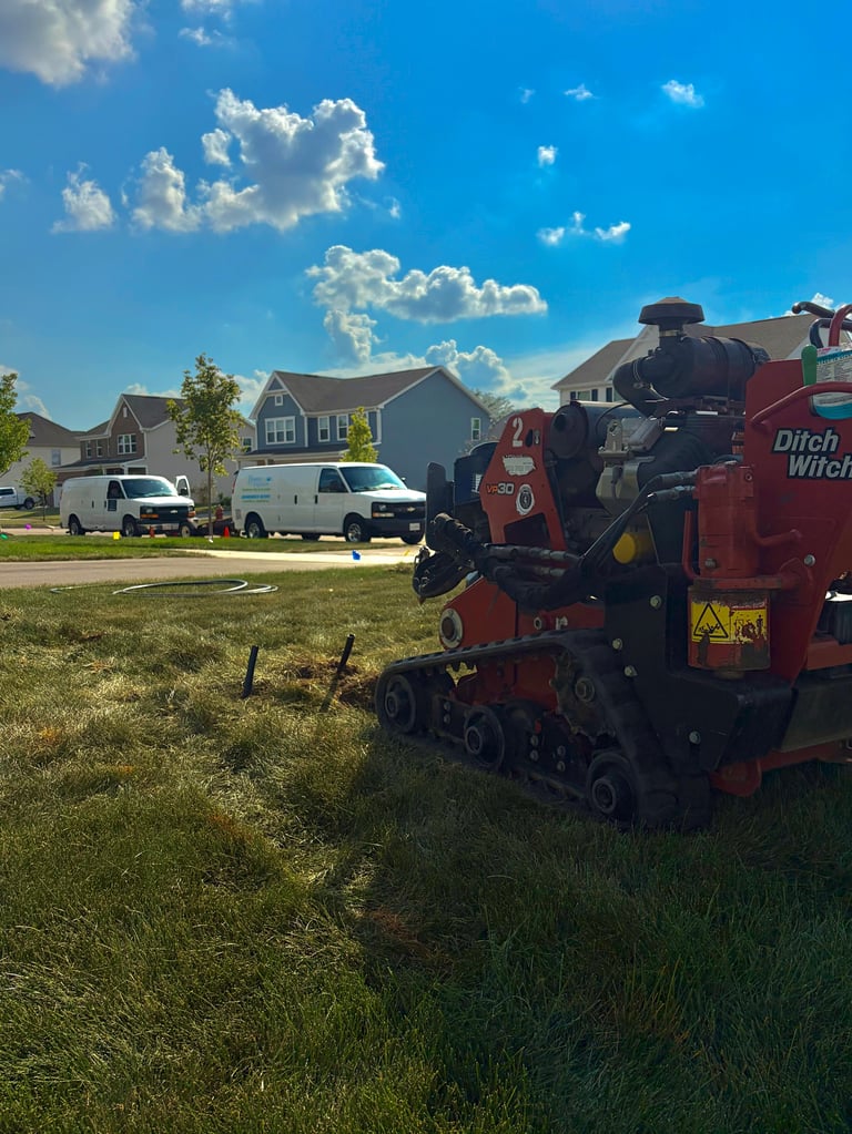 Red wood chipping machine parked on residential street with suburban houses and clear blue sky in background